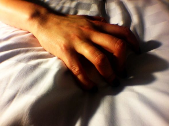 Picture of a hand grasping at a white bedsheet