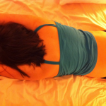 GOTN lying on the bed in a small blue-ish top, face down with her knickers pulled down just far enough to show her bum