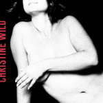 Picture of Christine Wild topless with her hand over her breasts, looking upwards from the frame