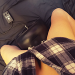 Person sitting astride The Cowgirl with bare legs, wearing a checked shirt