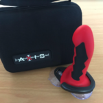 Black holder with AXIS written on it and red/black silicone dildo with suction cups