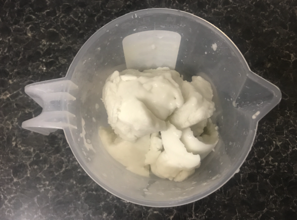 Plastic measuring jug with a large solid lump of white gunk in it