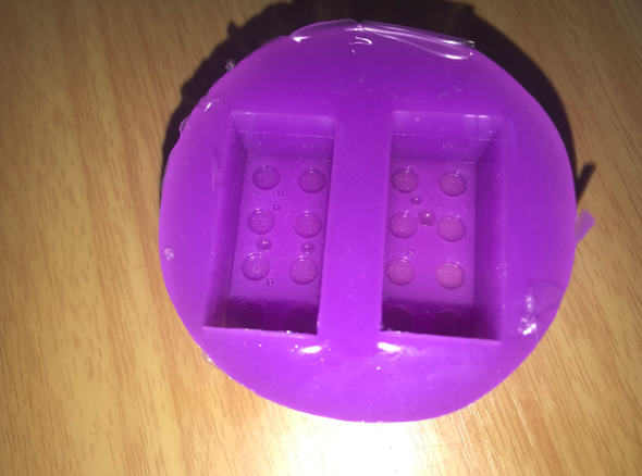 Round portion of purple silicone with the imprint of two lego bricks in it