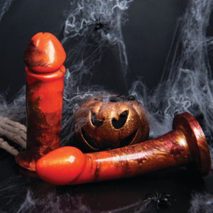 Orange and black dildos next to a pumpkin