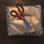 Gift wrapped in gold paper with scissors lying on top