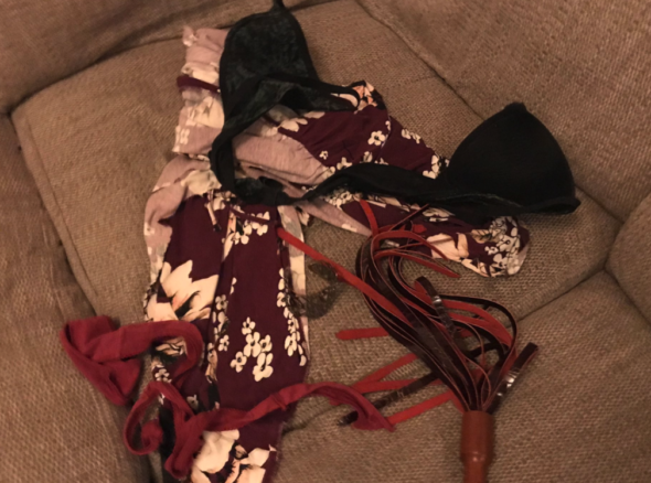 Pile of torn clothes including bra and purple dress with white flowers and a red thong, plus flogger