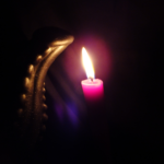 Golden tentacle reaches out towards a candlelight in the darkness