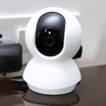 Smart camera with dome shape pointed at the viewer as if fulfilling their surveillance kink, plugged into mains plug behind it