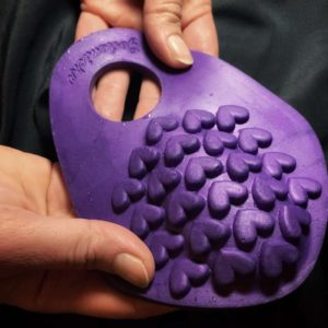 Purple silicone grind ring with a hole in it for cock and a heart texture to grind your clit against