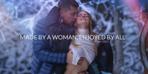 Image of a woman and a man kissing deeply in the snow, with the tagline 'made by a woman, enjoyed by all'
