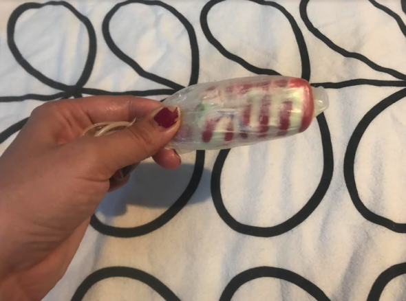 Image of GOTN's hand holding an ice lolly that has been safely wrapped inside two condoms