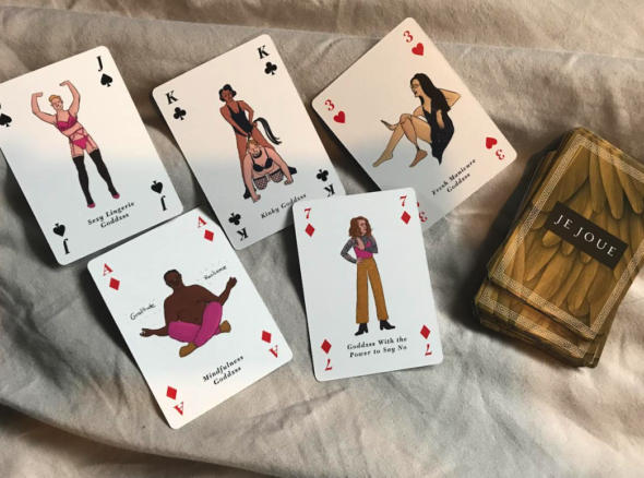 Image of playing cards with illustrations of people on including a kinky goddess wearing a body suit and dominating a person on their knees (king of clubs), a mindfulness goddess on the ace of diamonds card who is sitting topless and cross legged meditation, and a few more too. 
