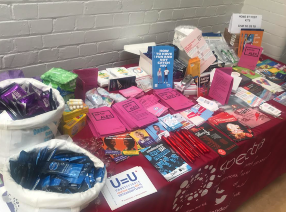 Image of a stand covered in leaflets with information about STIs, counselling, mentoring services and support