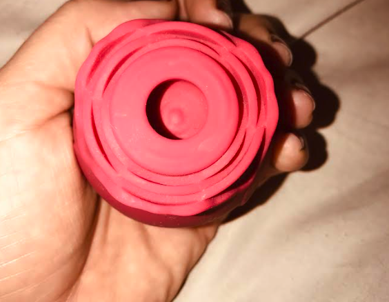 Image of the clit rose vibe from above - a red rose-shaped vibe with a small circular chamber in the centre where the bud would be