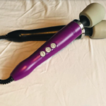 Two crossed Doxy wand vibrators - one black with a grey head, the other purple with a greay head