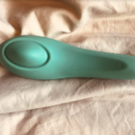 Green sex toy with oval plate on a wider head end, then tapered down to a narrow handle