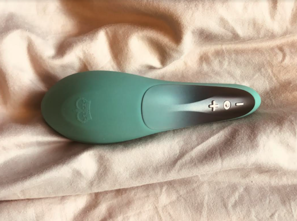 Green sex toy with one wide end, showing the buttons on reverse of the handle (gold plus, minus and circle symbols on a black background)