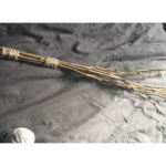 Lying on a grey duvet lies a birch made of eight hazel rods with buds/break points on them, bound together at two points at one end into a handle. the spray at the other end looks very painful indeed.