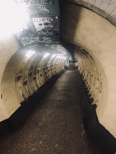 Long round foot tunnel with bright lighting and walls made of thick steel panels