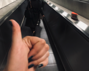 Moving walkway, like you get in an airport, with metal barriers either side and anonymous people walking in front