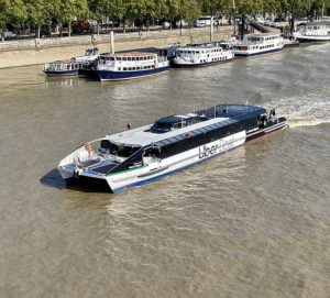 Shot from the sky of a clipper-style boat (about 150 capacity) carving through the thames