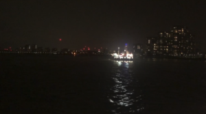 Rubbish picture of a lit ferry in the inky darkness, some london lights visible on the banks of the river