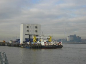 Shot of a car ferry by day, docked in a port on the edge of the thames