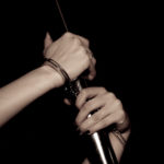 Hands cuffed to a silver pole, holding on to it