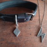 Black leather collar with a tag that reads 'prey' and a silver chain with lightning-bolt shaped tag which reads 'sir'
