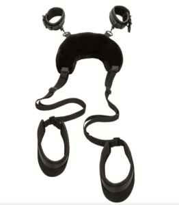 Black 'u' shaped pillow with short velcro wrist cuffs attached to the top, and longer straps with thick restraints for thighs attached to the bottom