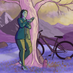 Woman in jacket and trousers leans against a tree casually munching on a sandwich - behind her, a bike leans against the tree and a view of beautiful mountains is highlighted by afternoon sunshine