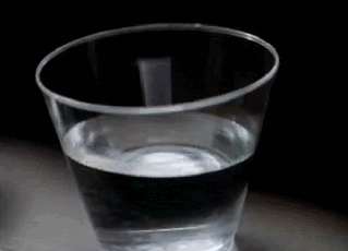 Gif of a plastic cup of water sitting on the dashboard of a car, something big/loud has obviously happened nearby because the water ripples ominously